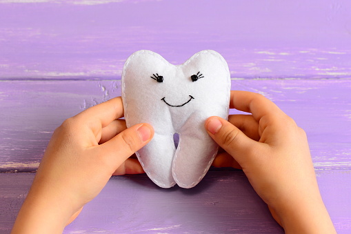 Hands holding a smiling tooth model symbolizing healthy teeth and preventive dental care. This represents maintaining strong and happy smiles at Hayden Dental Care.